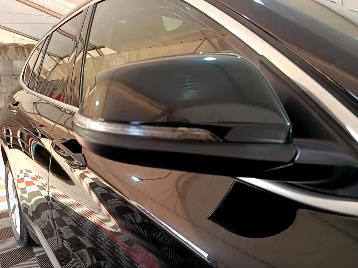 Gros plan sur le rétroviseur côté gauche noir brillant d’un BMW X1 sDrive20i Business Design 2020.