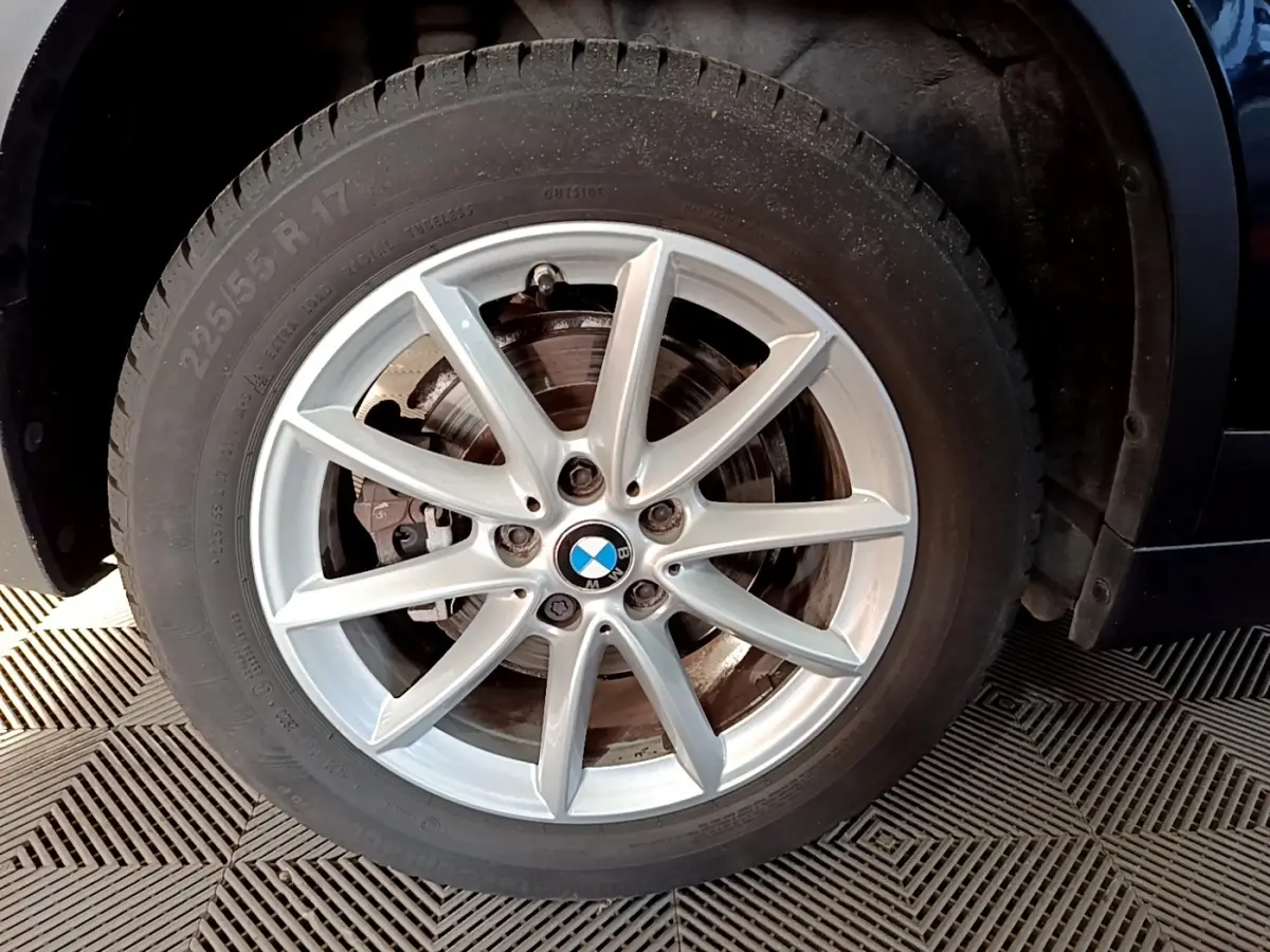 Gros plan sur la roue avant gauche avec jante alliage argentée du BMW X1 noir sDrive20i Business Design 2020.