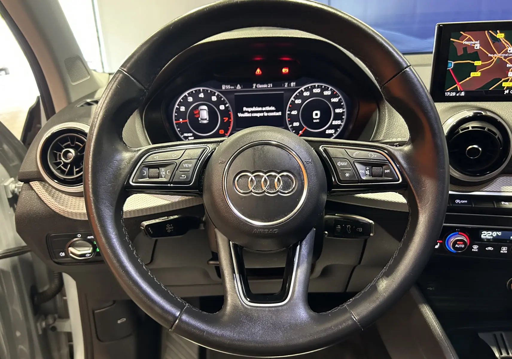 Vue intérieure centrée sur le volant cuir noir d'un Audi Q2 2023 avec tableau de bord digital et écran GPS.