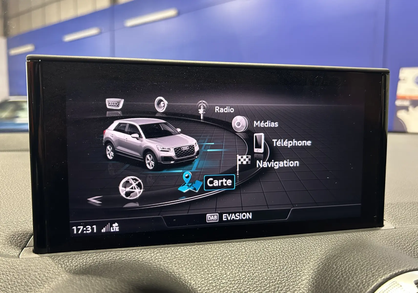 Écran du virtual cockpit montrant la navigation et un Audi Q2 gris en vue 3/4 avant dans l'interface multimédia.