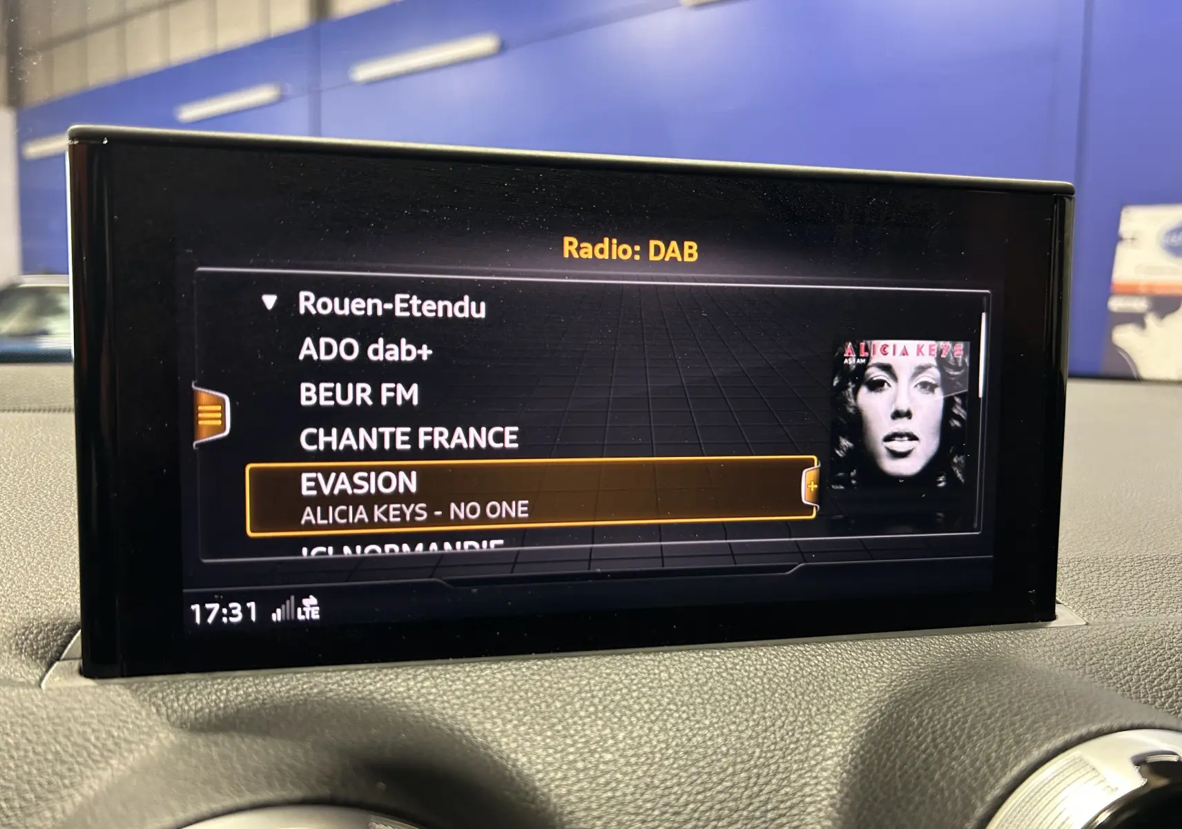 Écran central de l'Audi Q2 gris 2023 affichant la radio DAB avec la station EVASION en surbrillance.
