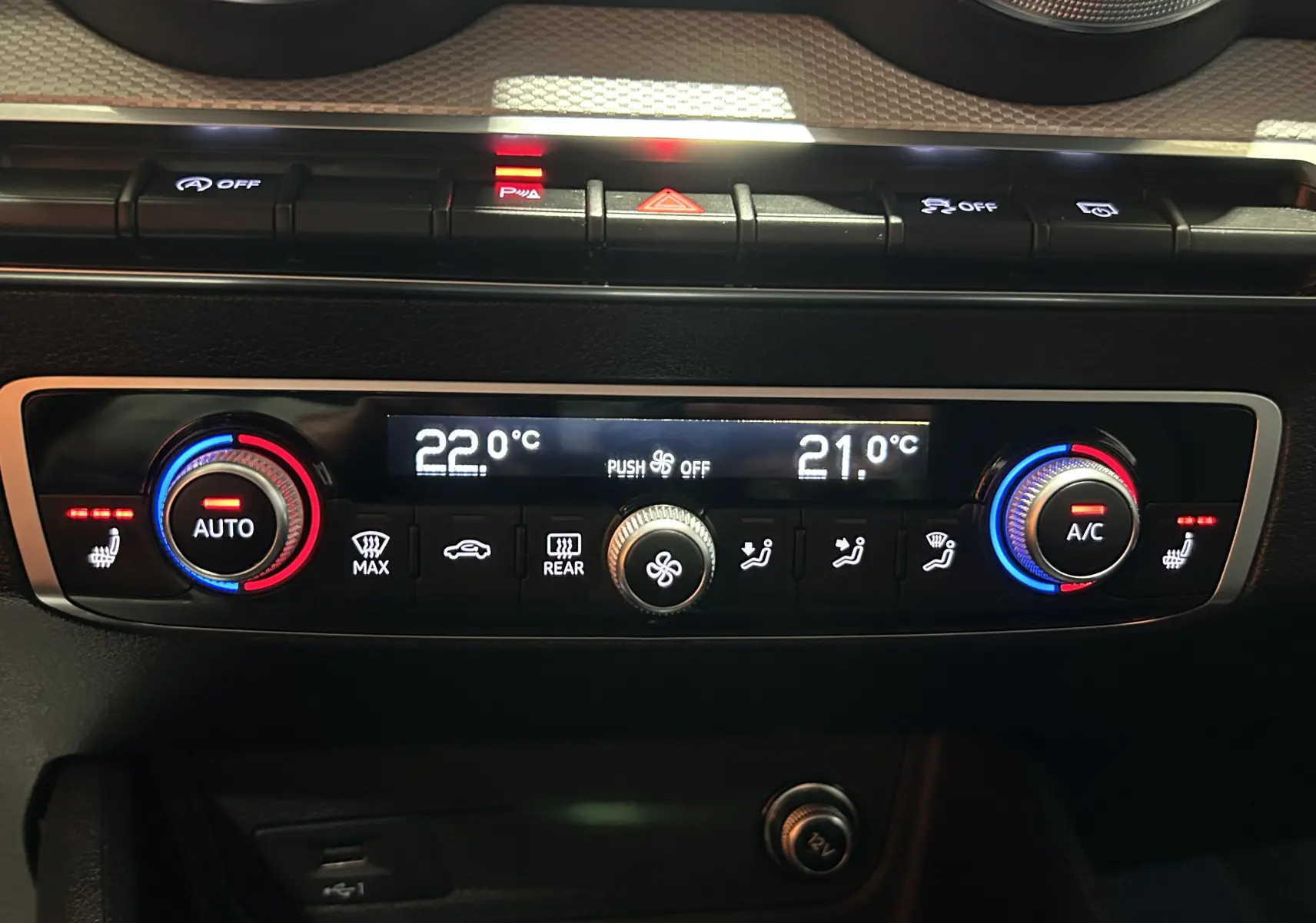 Panneau de climatisation double zone de l'Audi Q2 gris, avec réglages chauffants et affichage digital des températures.