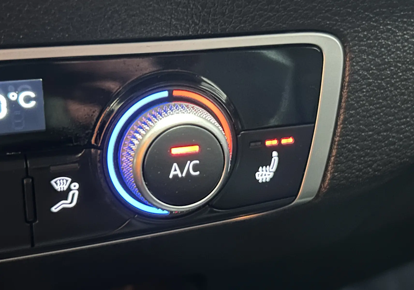 Gros plan sur le bouton de climatisation et siège chauffant du tableau de bord de l'Audi Q2 gris 2023.