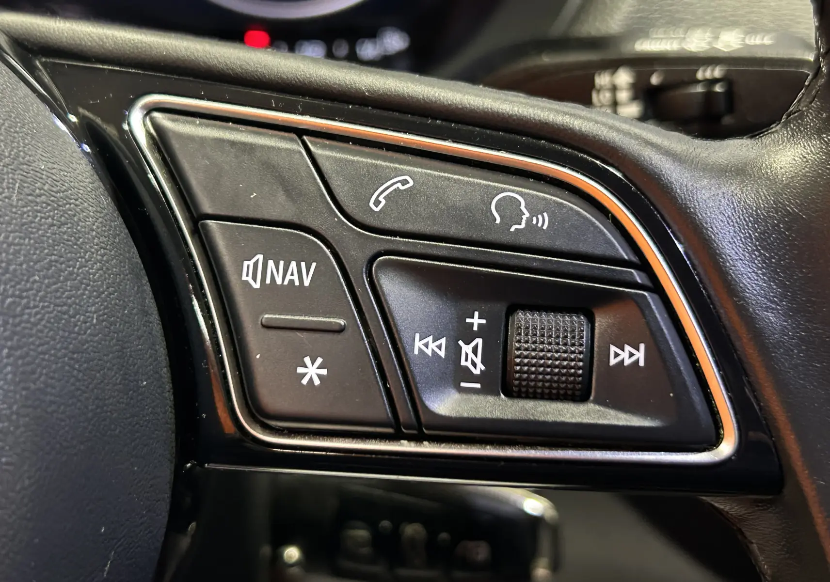 Gros plan sur les commandes audio et navigation au volant en cuir noir de l'Audi Q2 gris TFSI 110 2023.