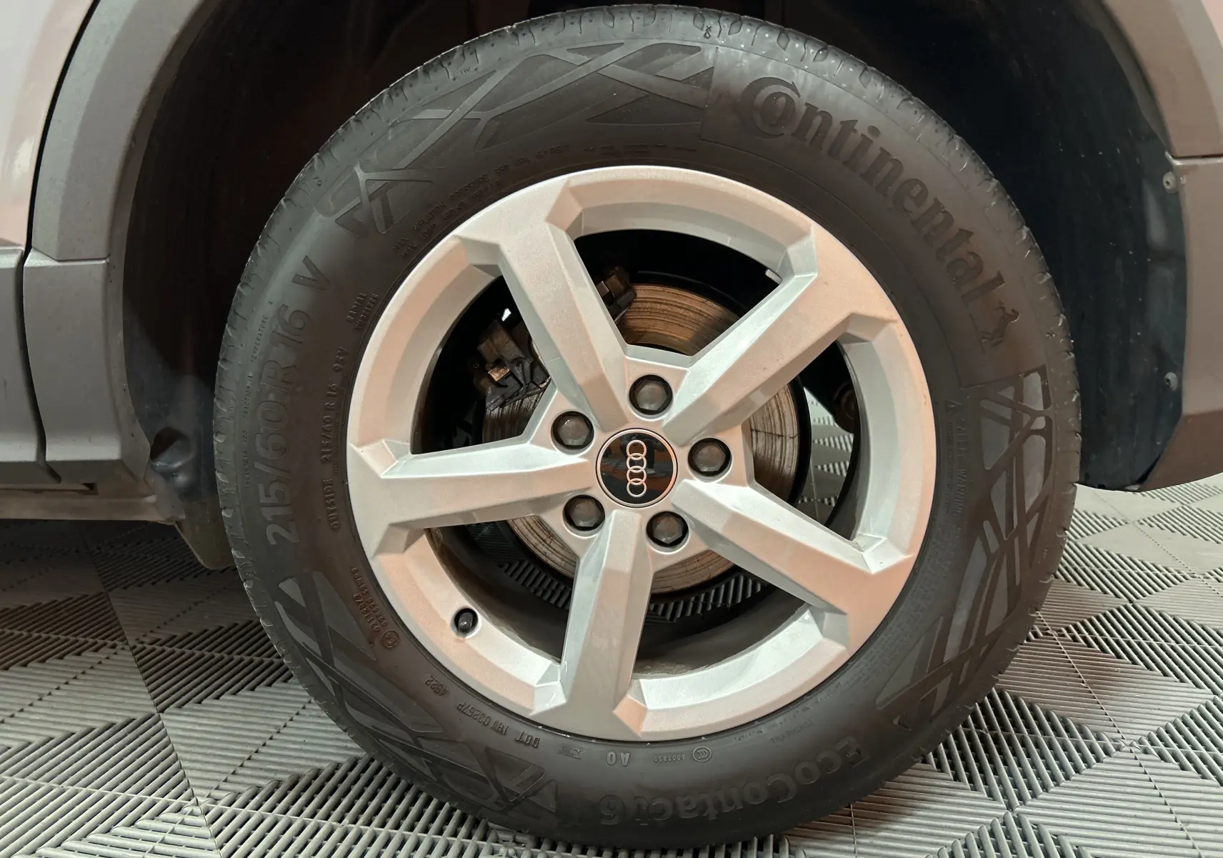 Gros plan sur la roue avant gauche gris clair de l’Audi Q2 2023 avec jante en alliage et logo Audi central.