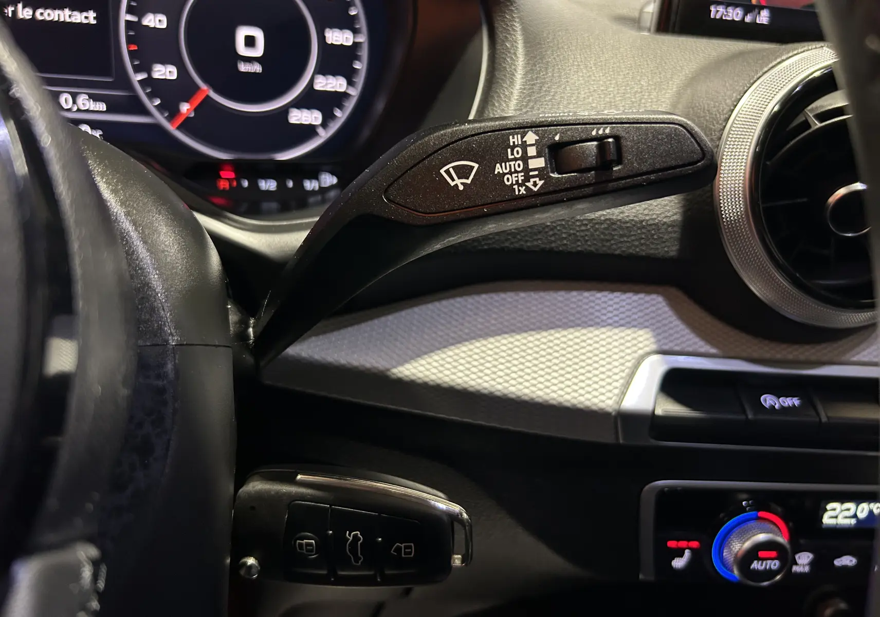 Détail intérieur côté gauche du tableau de bord gris d’Audi Q2 2023 avec commandes essuie-glace et climatisation digitale.