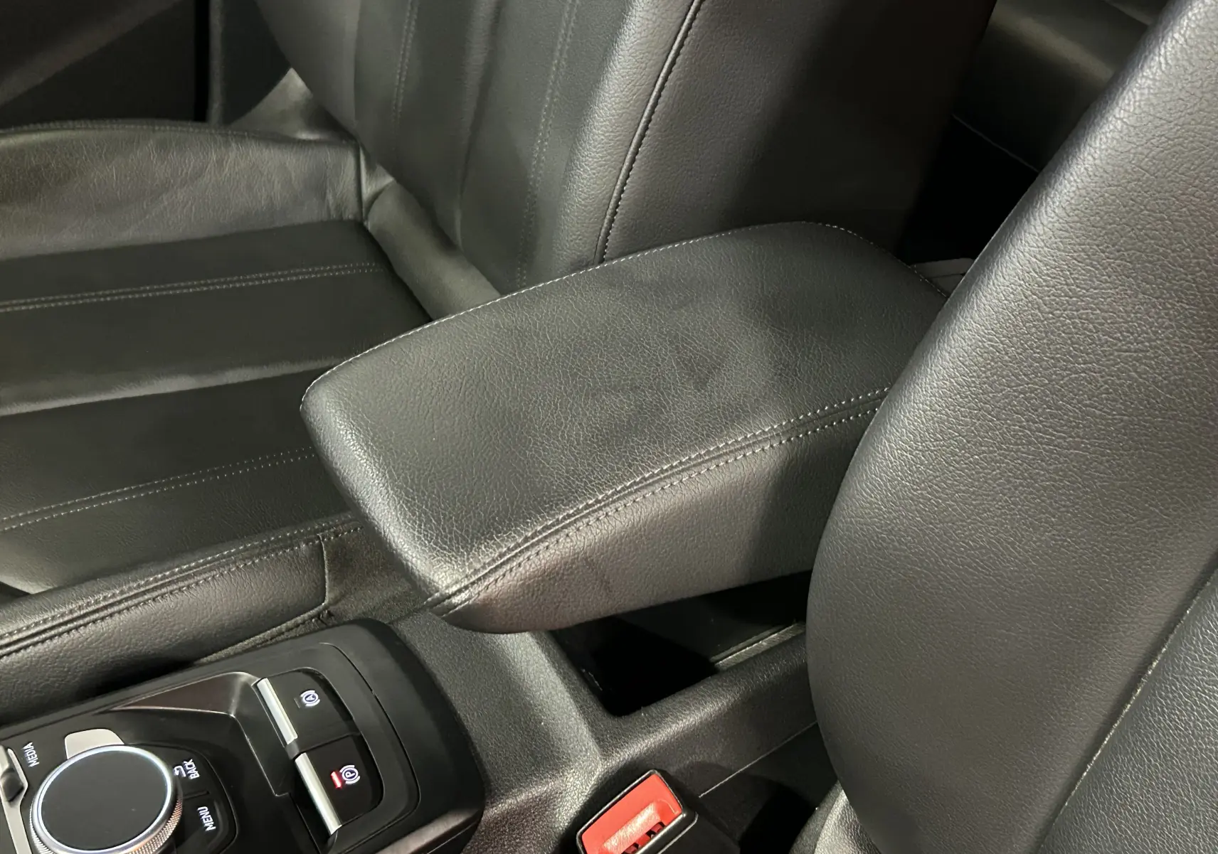 Gros plan sur l'accoudoir central en cuir noir et la console centrale d'un Audi Q2 TFSI 110 gris, intérieur cuir.