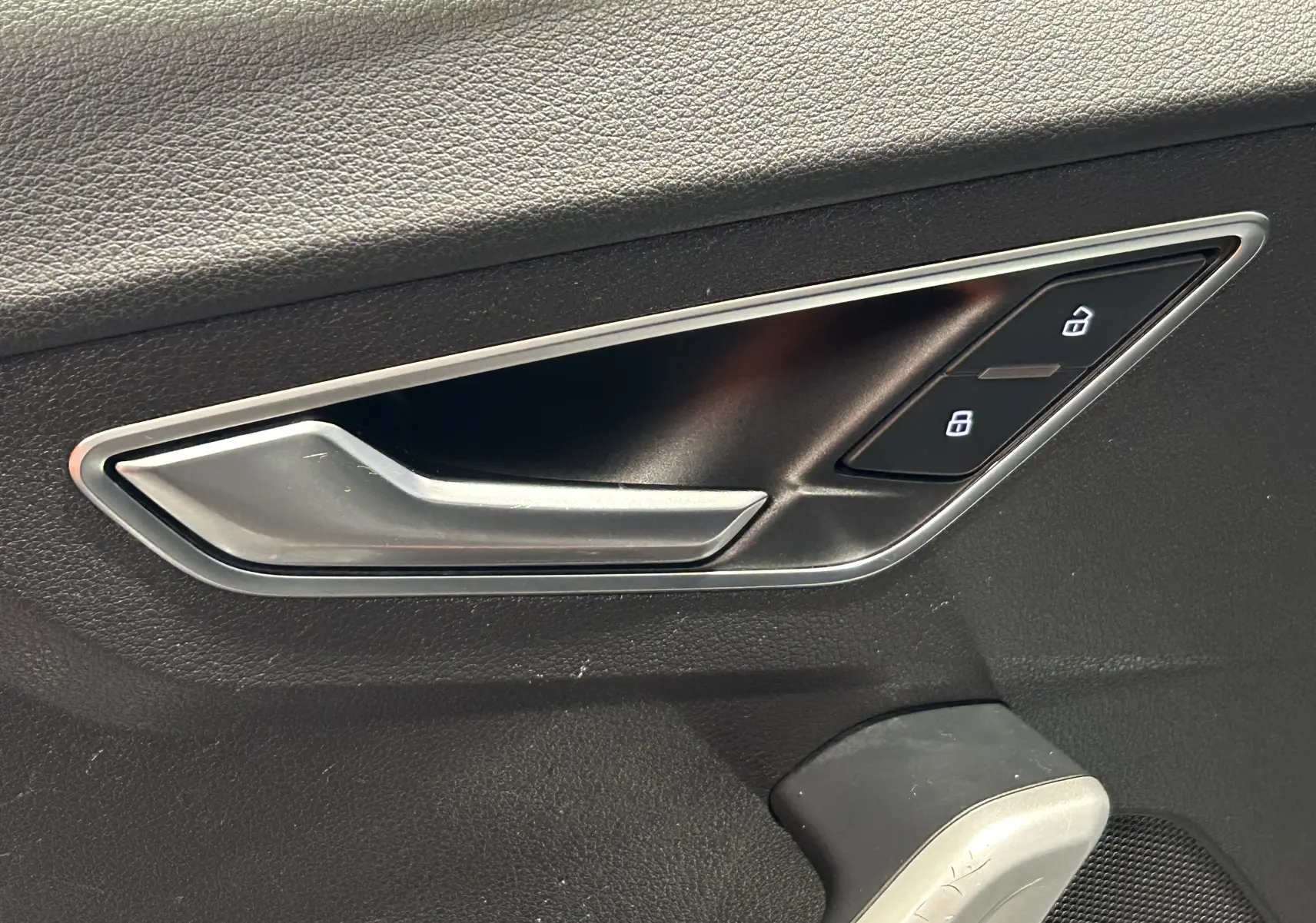 Gros plan sur la poignée intérieure côté gauche d'une Audi Q2 2023 gris avec commandes de verrouillage intégrées.