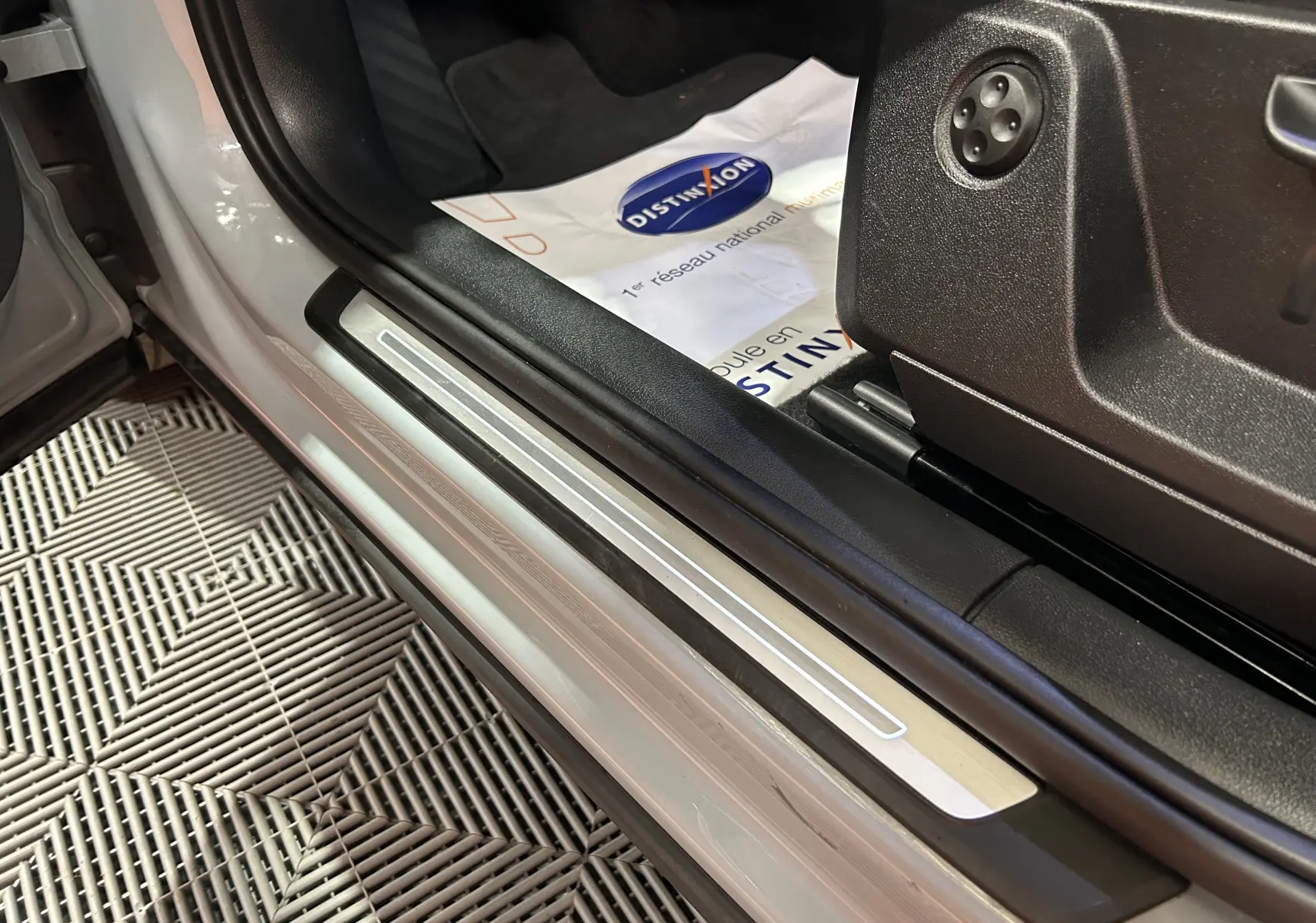 Gros plan sur la marche d'entrée côté conducteur d'un Audi Q2 gris, avec seuil en aluminium et intérieur noir.