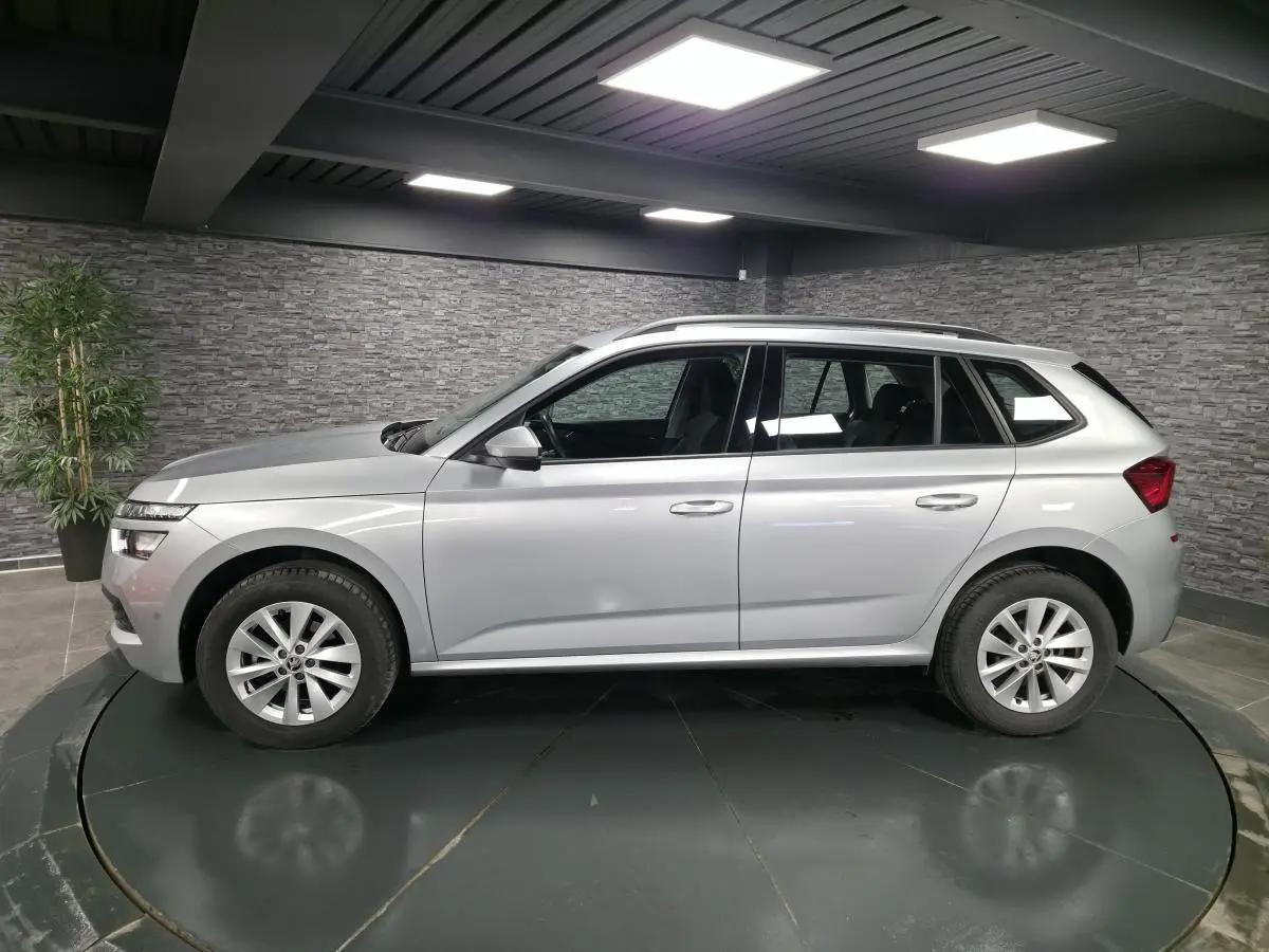 Vue de profil côté gauche d’un Skoda Kamiq gris métallisé 2023 en intérieur avec jantes alliage 16 pouces.