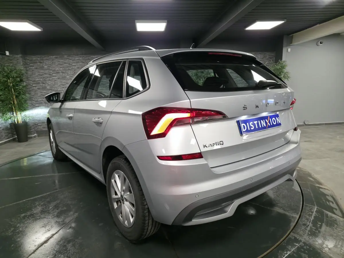 Vue 3/4 arrière droite du Skoda Kamiq gris métallisé avec feux arrière LED et jantes alliage 16 pouces en showroom.