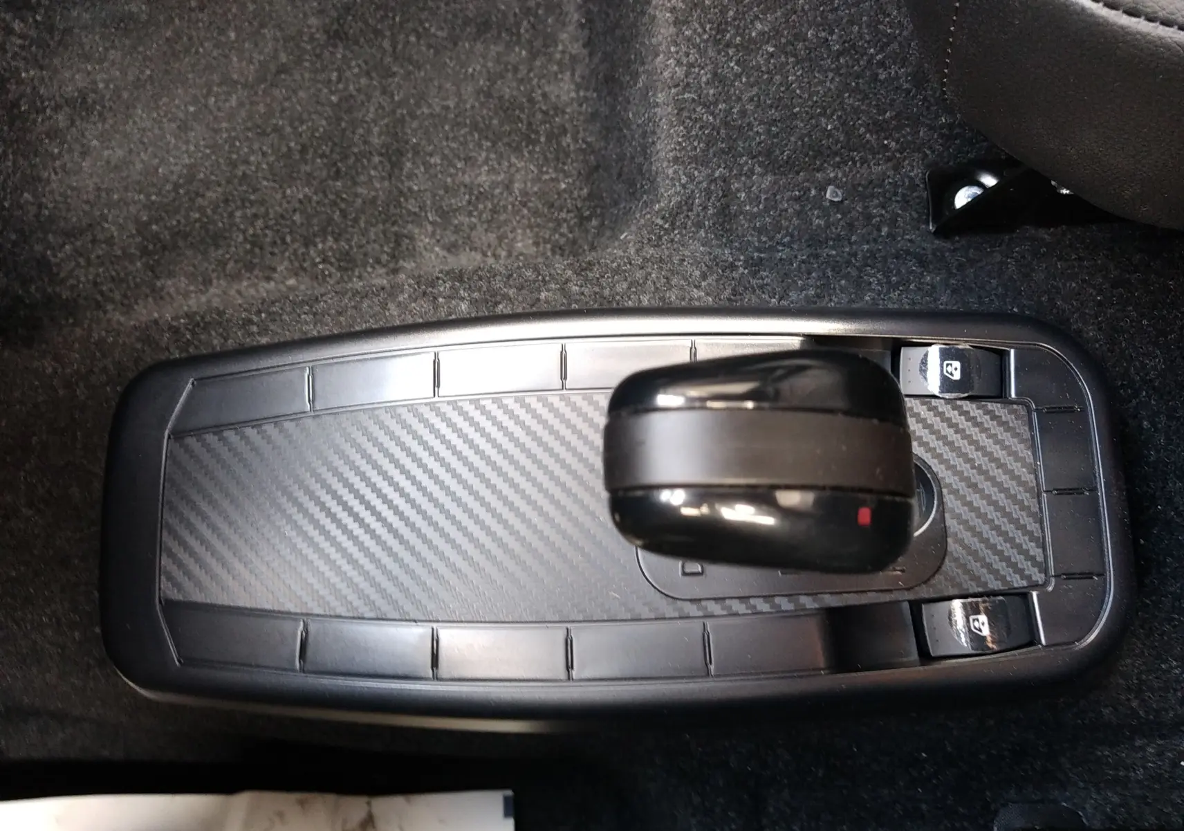Vue plongeante sur la console centrale avec levier de vitesse noir et finition carbone dans une Ligier Myli REVO D+ MAX gris graphite.