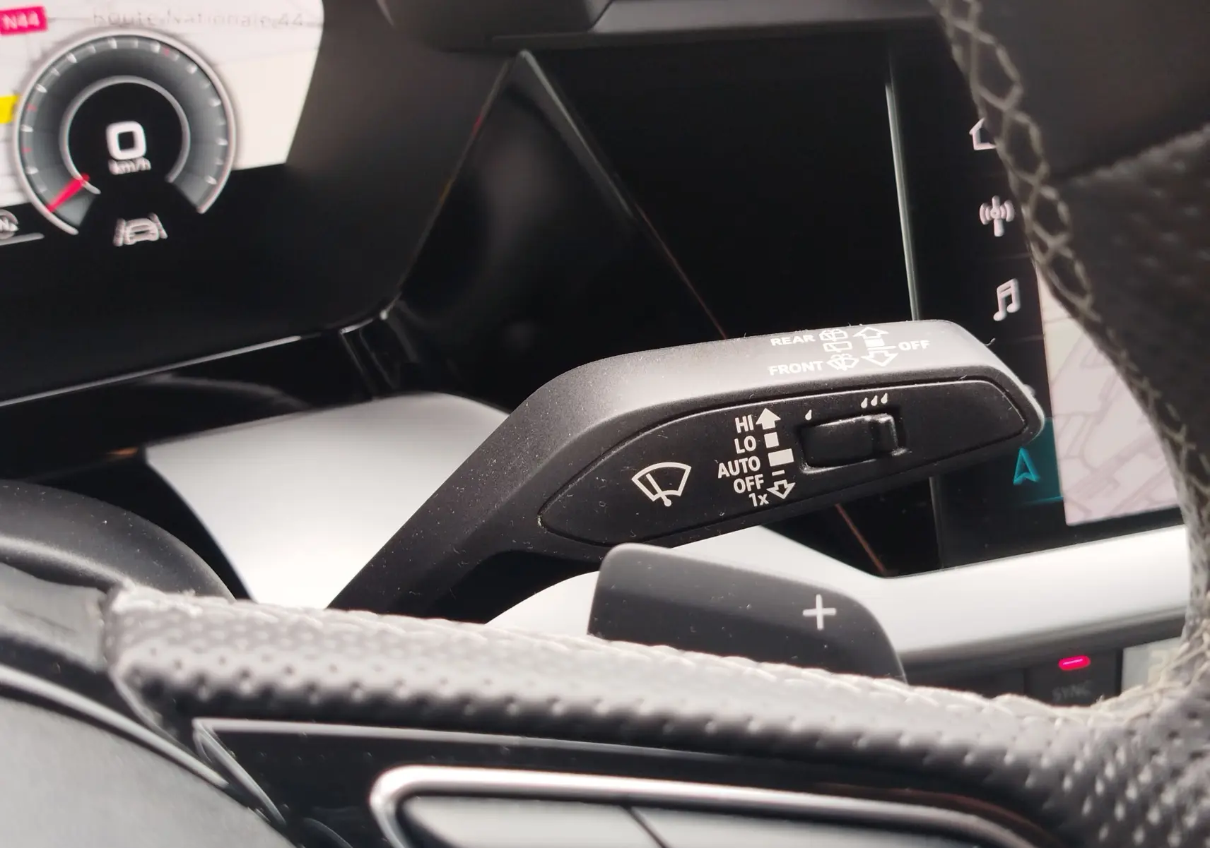 Gros plan sur la commande d’essuie-glace à gauche du volant dans l’habitacle d’une Audi A3 Sportback blanc Glacier 2022.
