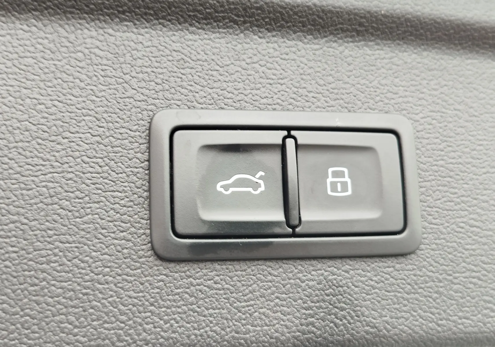Gros plan sur les boutons d'ouverture du coffre et de verrouillage intérieur d'une Audi A3 Sportback blanc glacier.