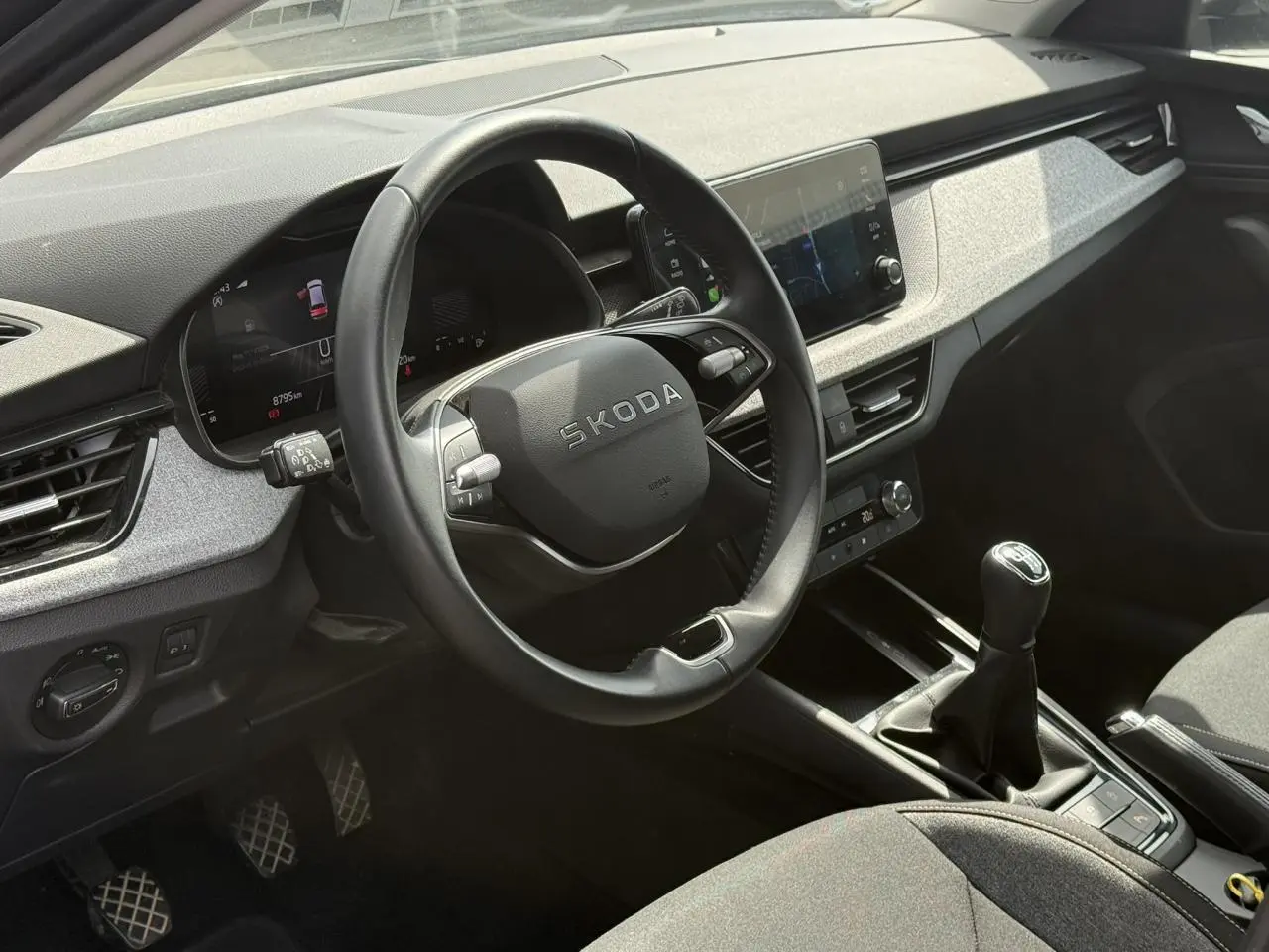 Vue intérieure côté conducteur du Skoda Scala TSI 116 gris graphite, volant cuir multifonctions et levier de vitesses manuel.