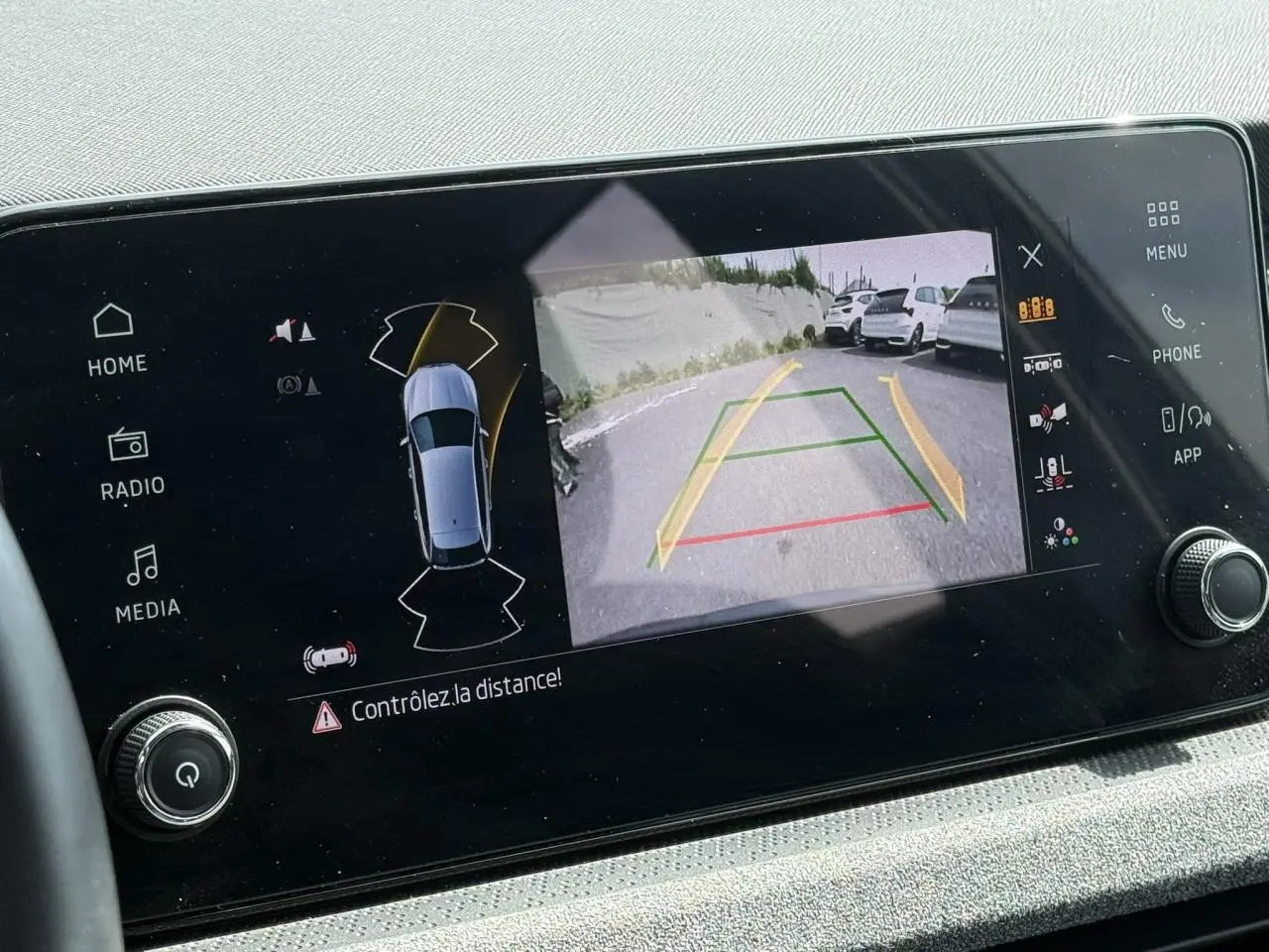 Écran central montrant la caméra de recul active avec vue arrière et alertes de distance du Skoda Scala gris graphite.