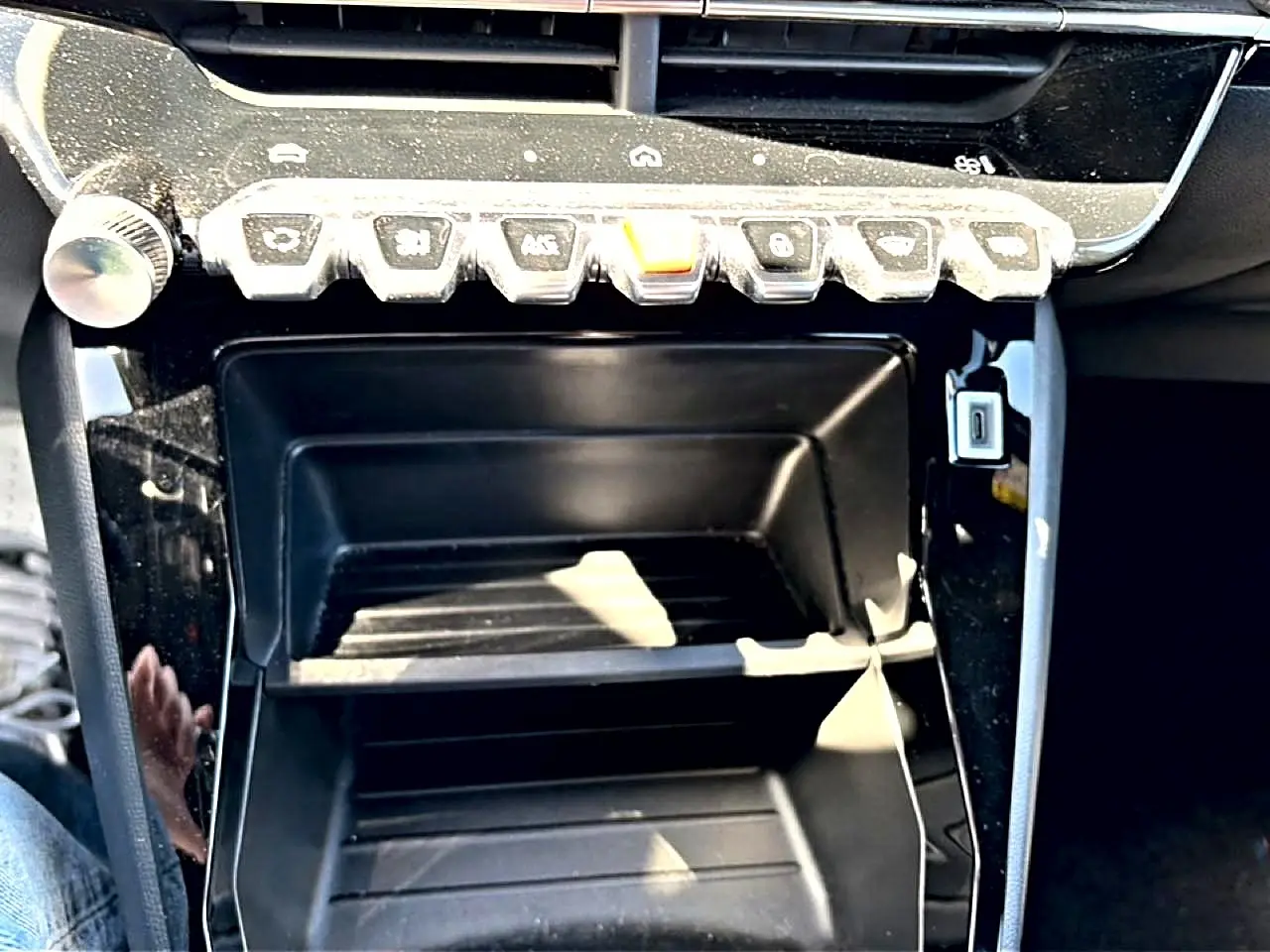 Gros plan sur la console centrale noire brillante du Peugeot 2008 1.2 100 style avec boutons de commande en rangée.