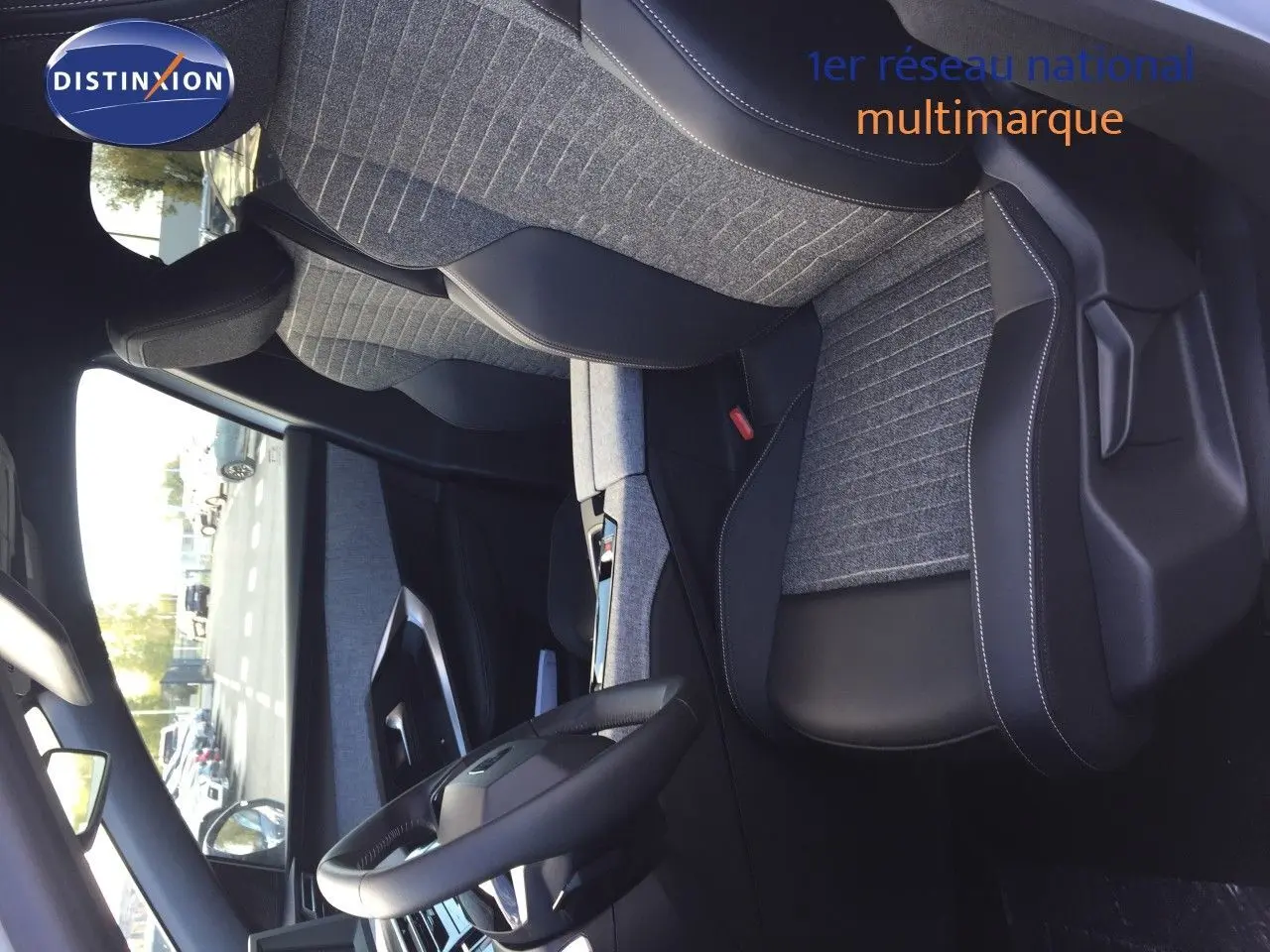 Intérieur du Peugeot 5008 Hybrid 2025, vue côté conducteur, sièges tissu gris et cuir noir avec coutures blanches.