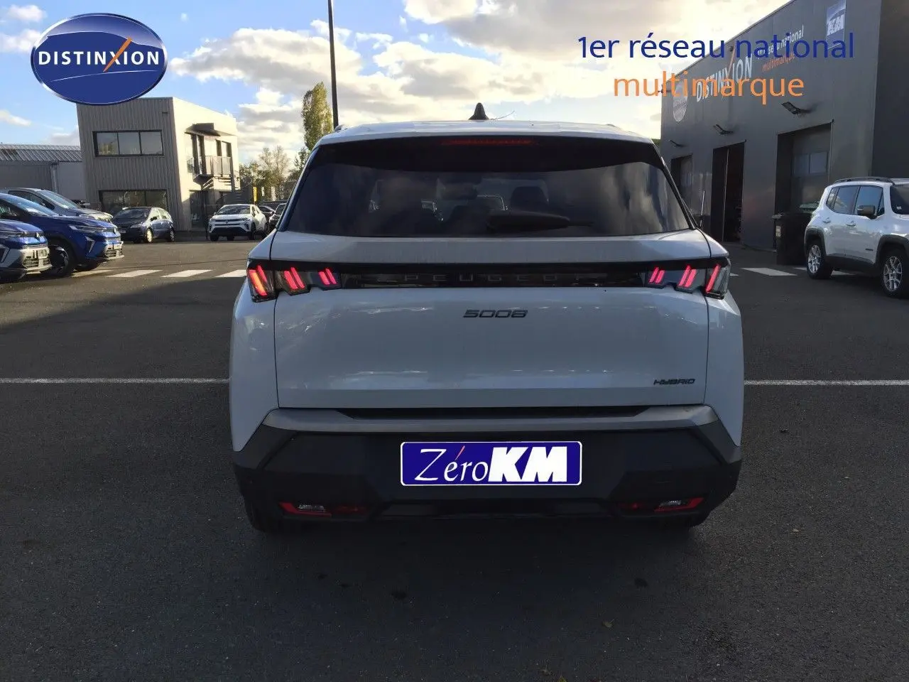 Vue arrière d'un Peugeot 5008 blanc Okenite Metal avec feux LED caractéristiques allumés sur parking extérieur.
