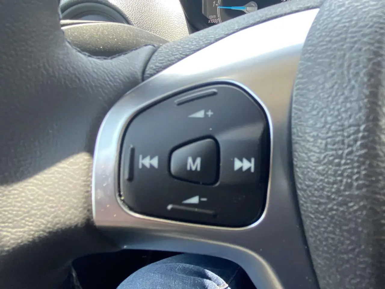 Gros plan sur les commandes audio au volant cuir noir du Ford Tourneo Courier blanc 2022, version Trend.