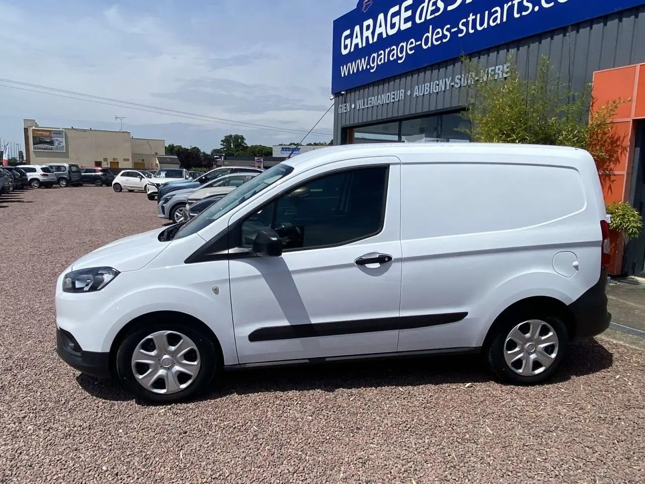 Fourgon Ford Tourneo Courier blanc vu de profil côté gauche, avec porte latérale coulissante et enjoliveurs cache moyeu.