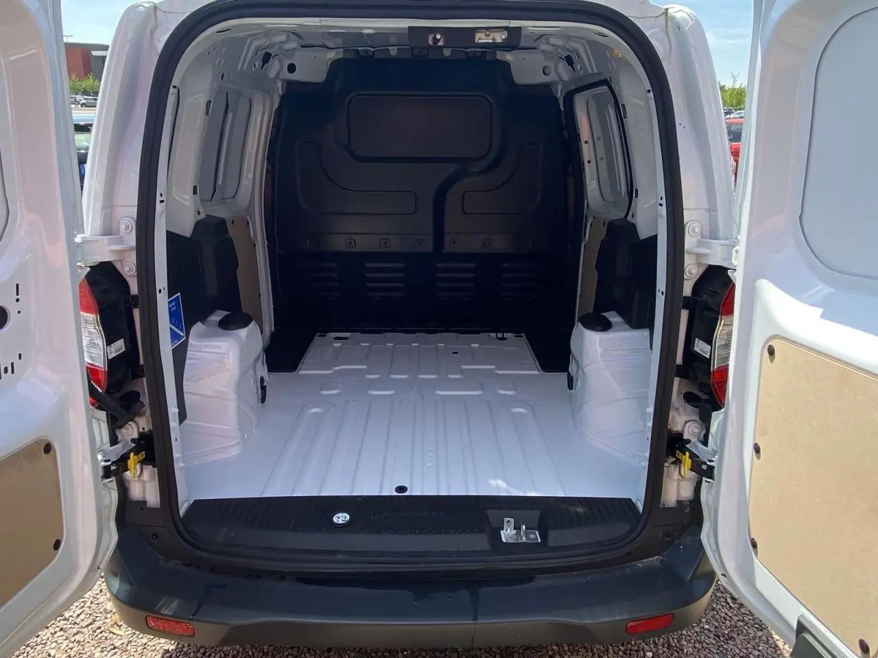 Vue arrière du fourgon blanc Ford Tourneo Courier 2022 avec portes battantes ouvertes dévoilant l'espace de chargement vide.