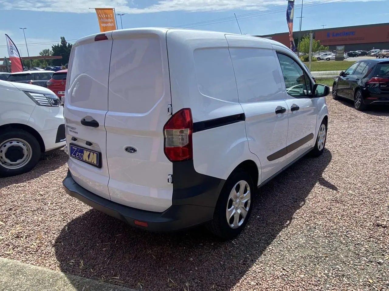 Fourgon Ford Tourneo Courier blanc vu en 3/4 arrière droit, avec portes arrière battantes et porte latérale coulissante.