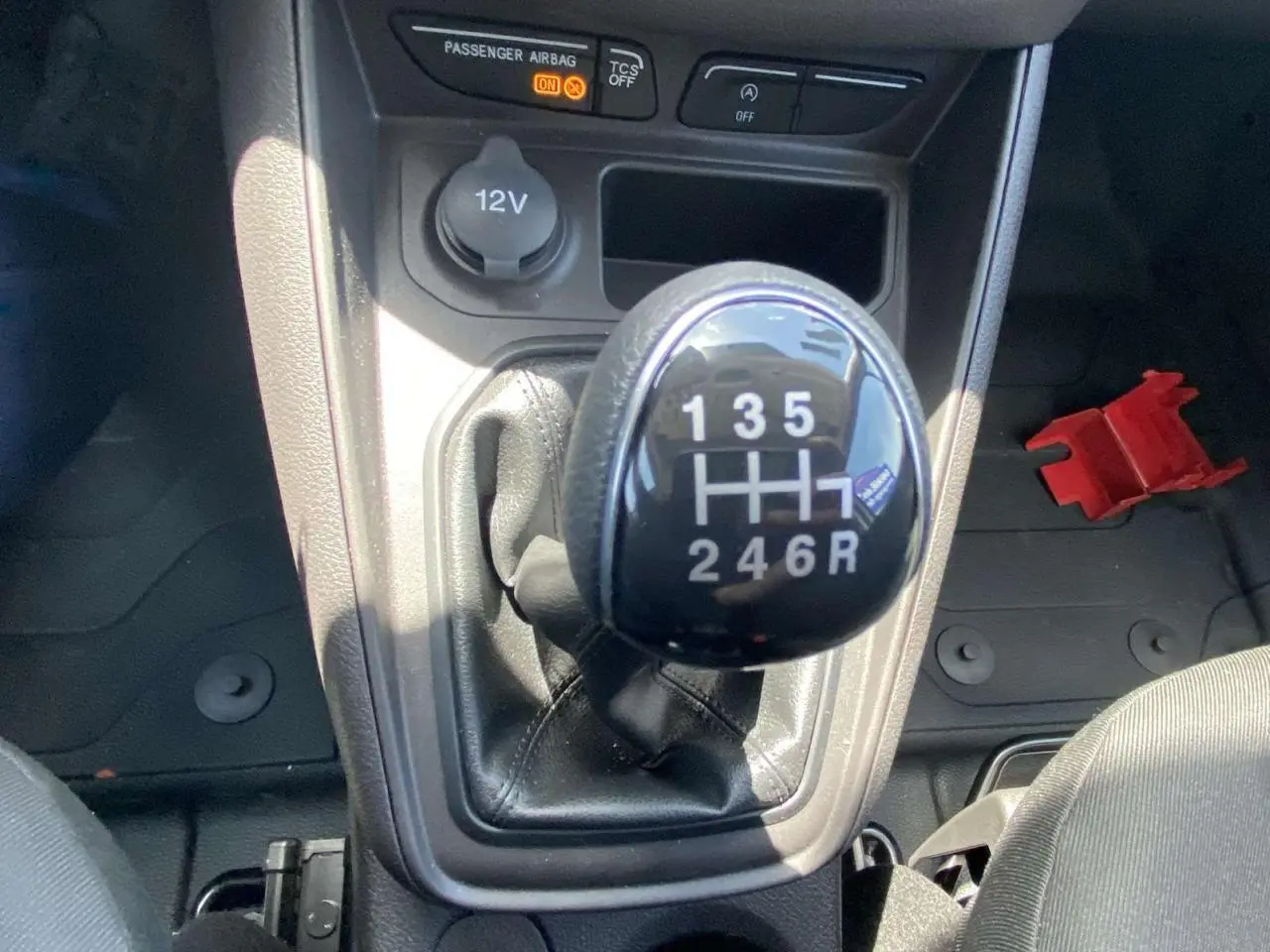 Gros plan sur le levier de vitesses manuel en cuir du Ford Tourneo Courier 2022, intérieur noir avec prise 12V visible.