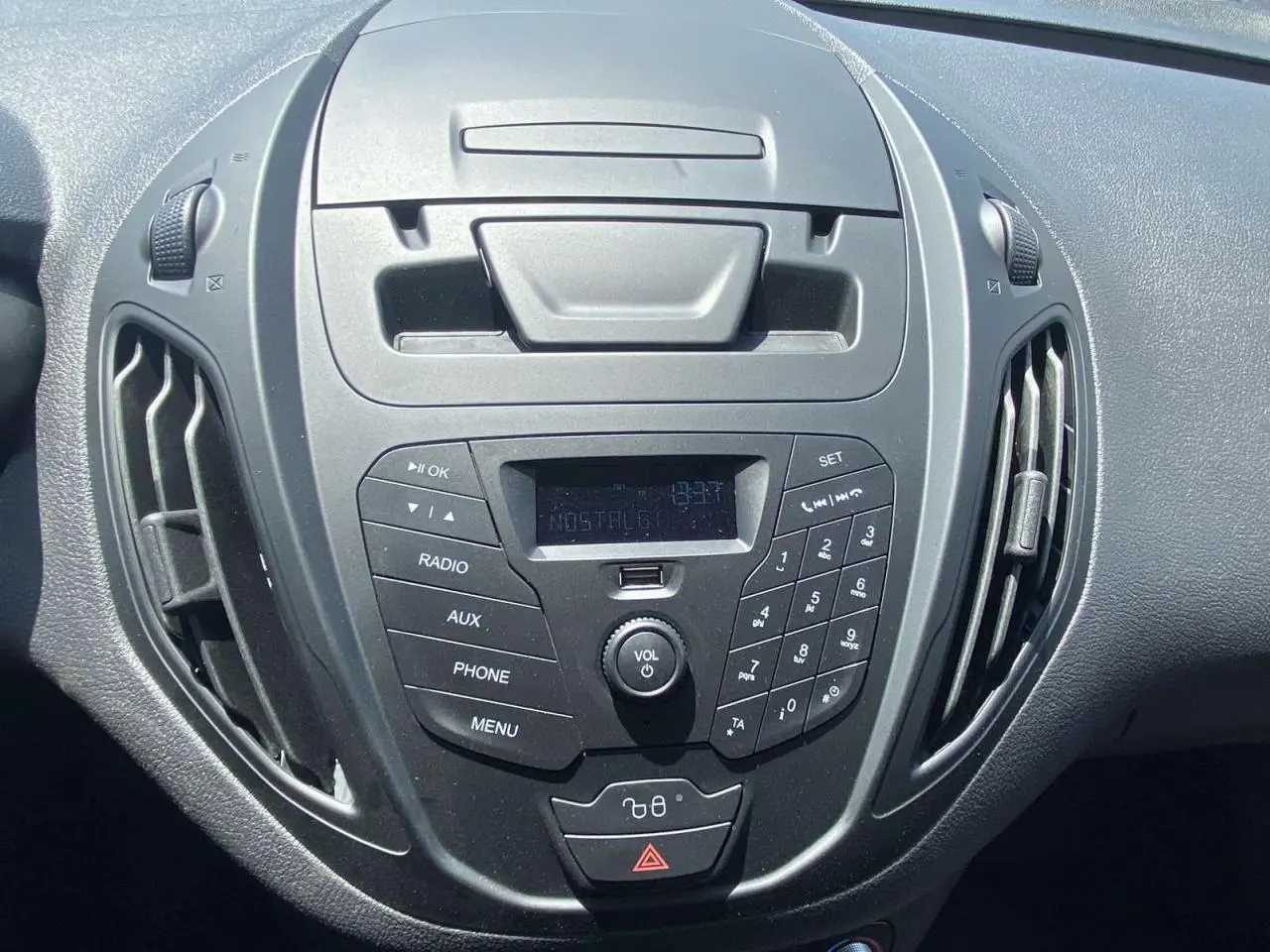 Vue rapprochée du tableau de bord noir du Ford Tourneo Courier 2022, mettant en valeur la console centrale avec radio et commandes.