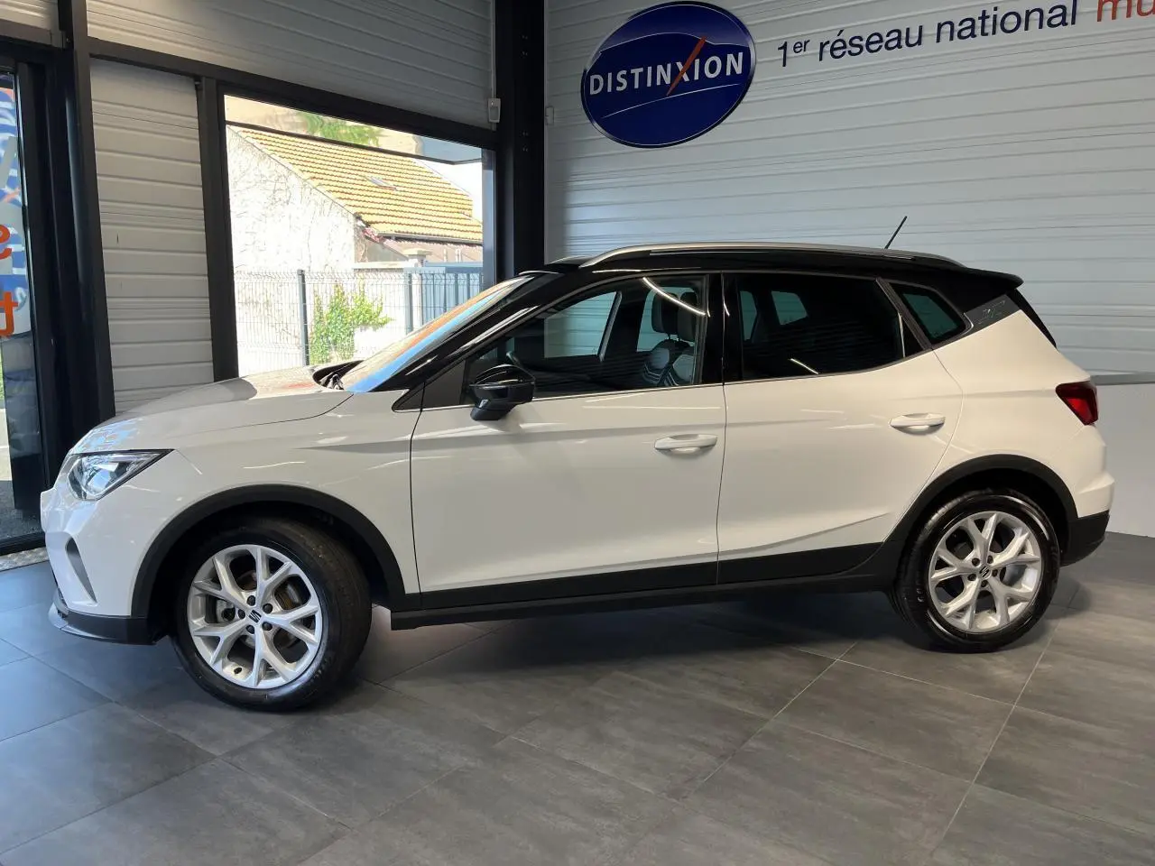 SEAT ARONA blanc Nevada vue de profil côté gauche en intérieur avec toit noir et jantes alliage 16 pouces.