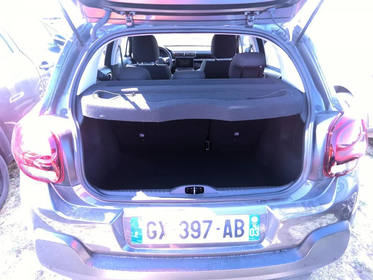 Vue arrière ouverte sur coffre d'une Citroën C3 gris foncé 2024 avec banquette et intérieur visibles.