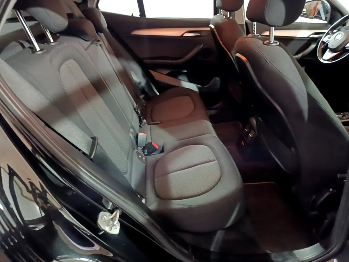 Vue intérieure côté gauche sur les sièges arrière noirs et l'avant de la BMW X2 sDrive18i Lounge DKG7 2023.