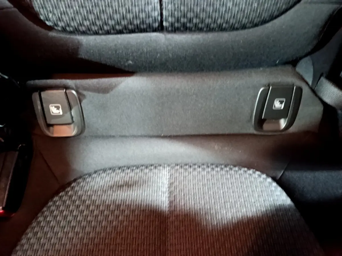 Détail des commandes de rabattement des sièges arrière sur banquette tissu gris du BMW X2 noir 2023.