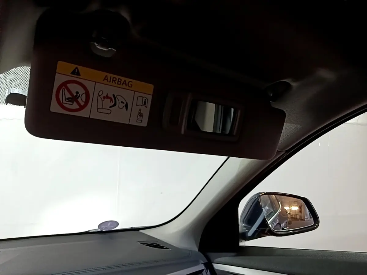 Vue intérieure côté conducteur du BMW X2 sDrive18i Lounge 2023, avec pare-soleil et rétroviseur noir visible.