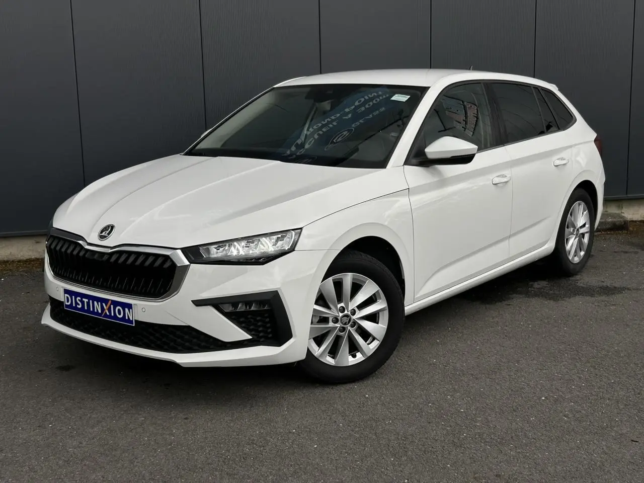 Vue 3/4 avant droite d'une Skoda Scala blanc Candy avec jantes alliage et vitres surteintées.