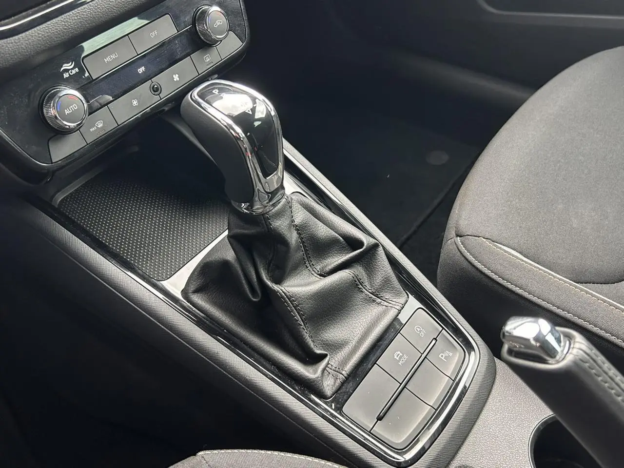 Gros plan intérieur sur la console centrale de la Skoda Scala TSI 116 DSG7 avec levier de vitesse et commandes noires.