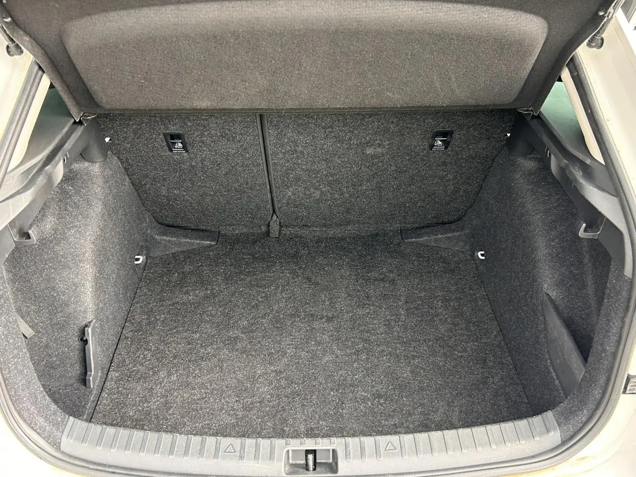 Coffre ouvert vu de l'arrière d'une Skoda Scala blanc Candy, montrant l'espace de chargement vide et tapissé.