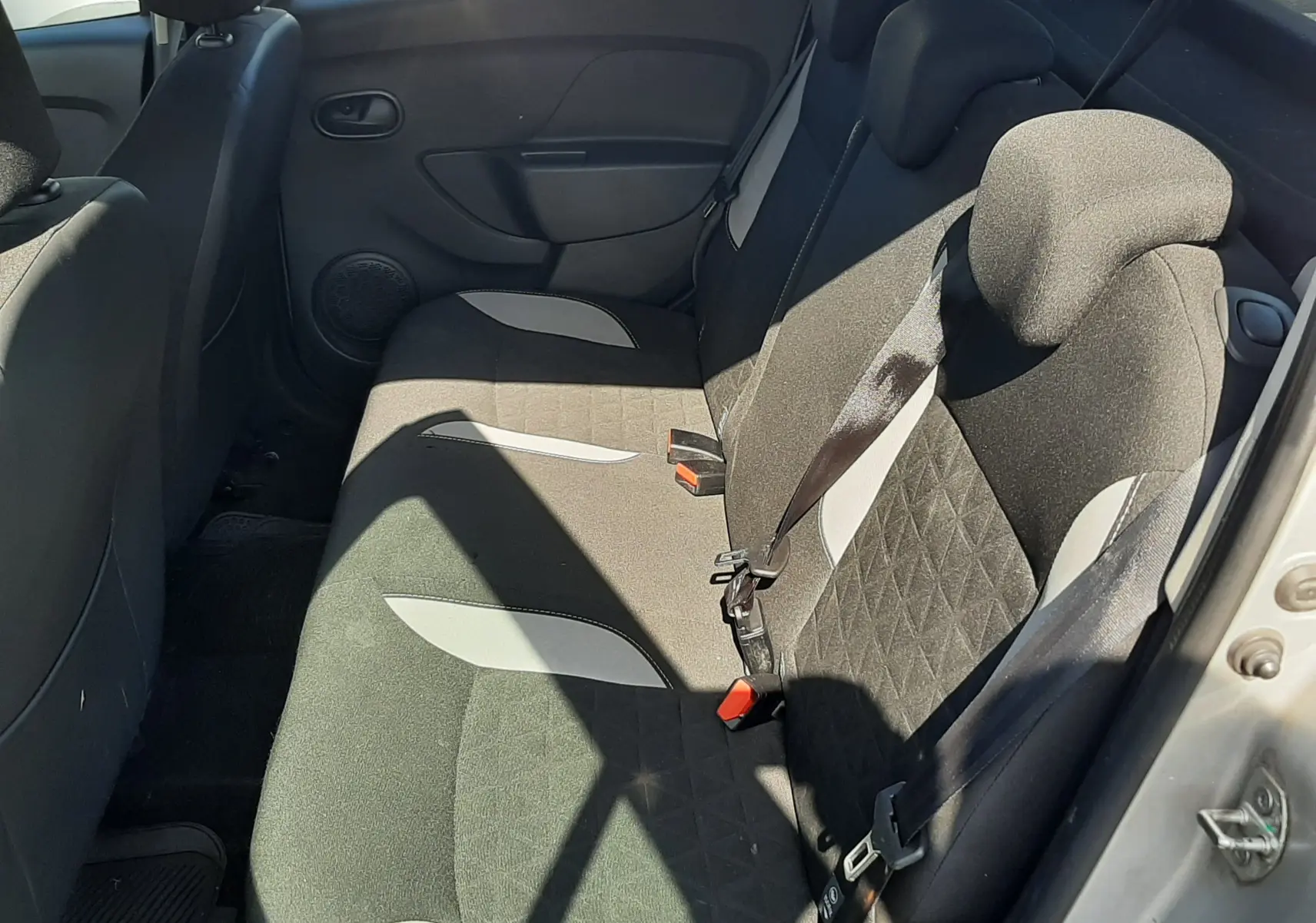 Vue intérieure côté droit montrant les sièges arrière en tissu gris noir de la Dacia Sandero Stepway gris platine 2016.