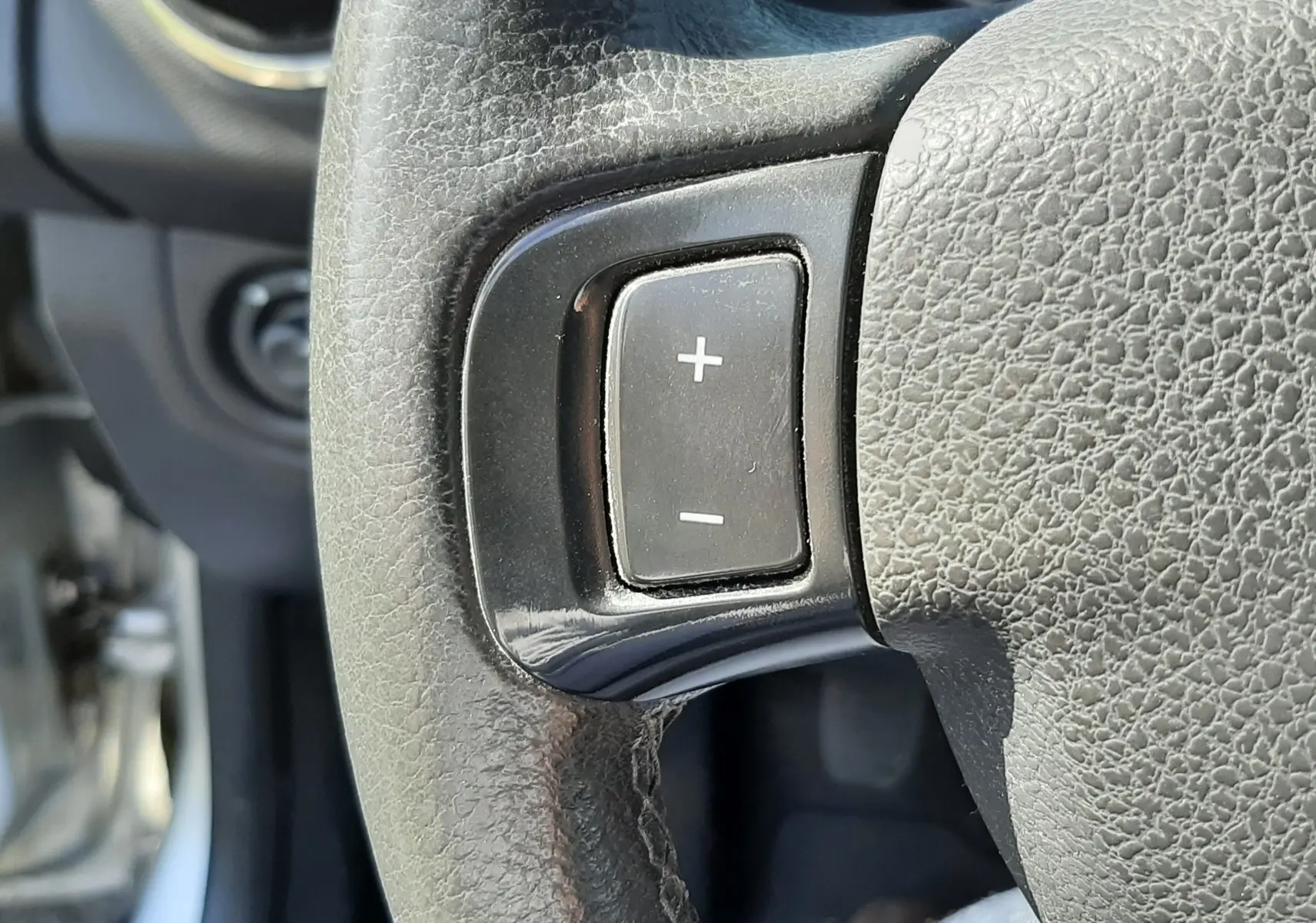 Gros plan sur le bouton de réglage du volume sur le volant en cuir noir du Dacia Sandero Stepway gris platine 2016.