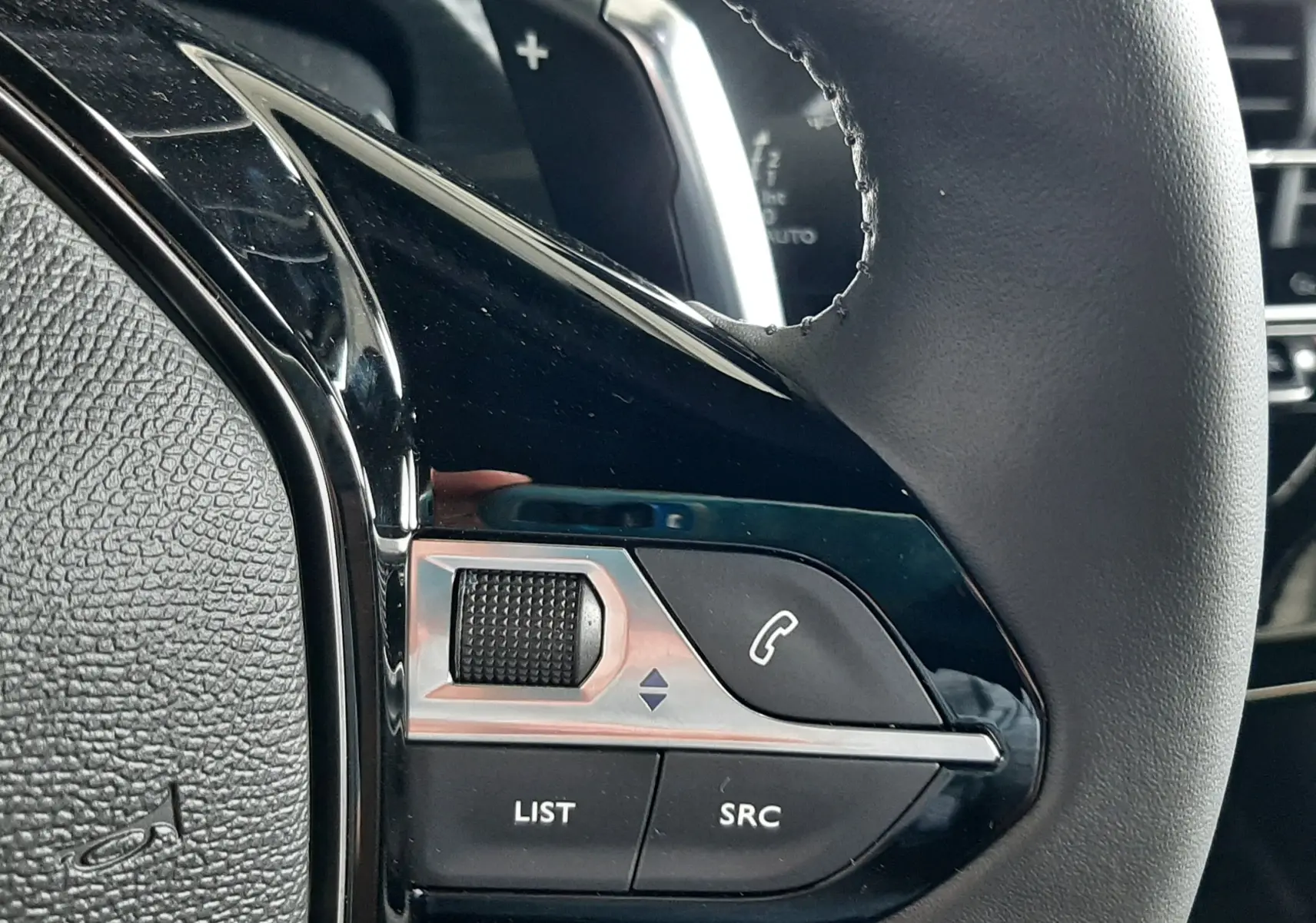 Gros plan sur les commandes gauche du volant noir du Peugeot 2008 1.2 Hybrid 145ch Allure 2025.