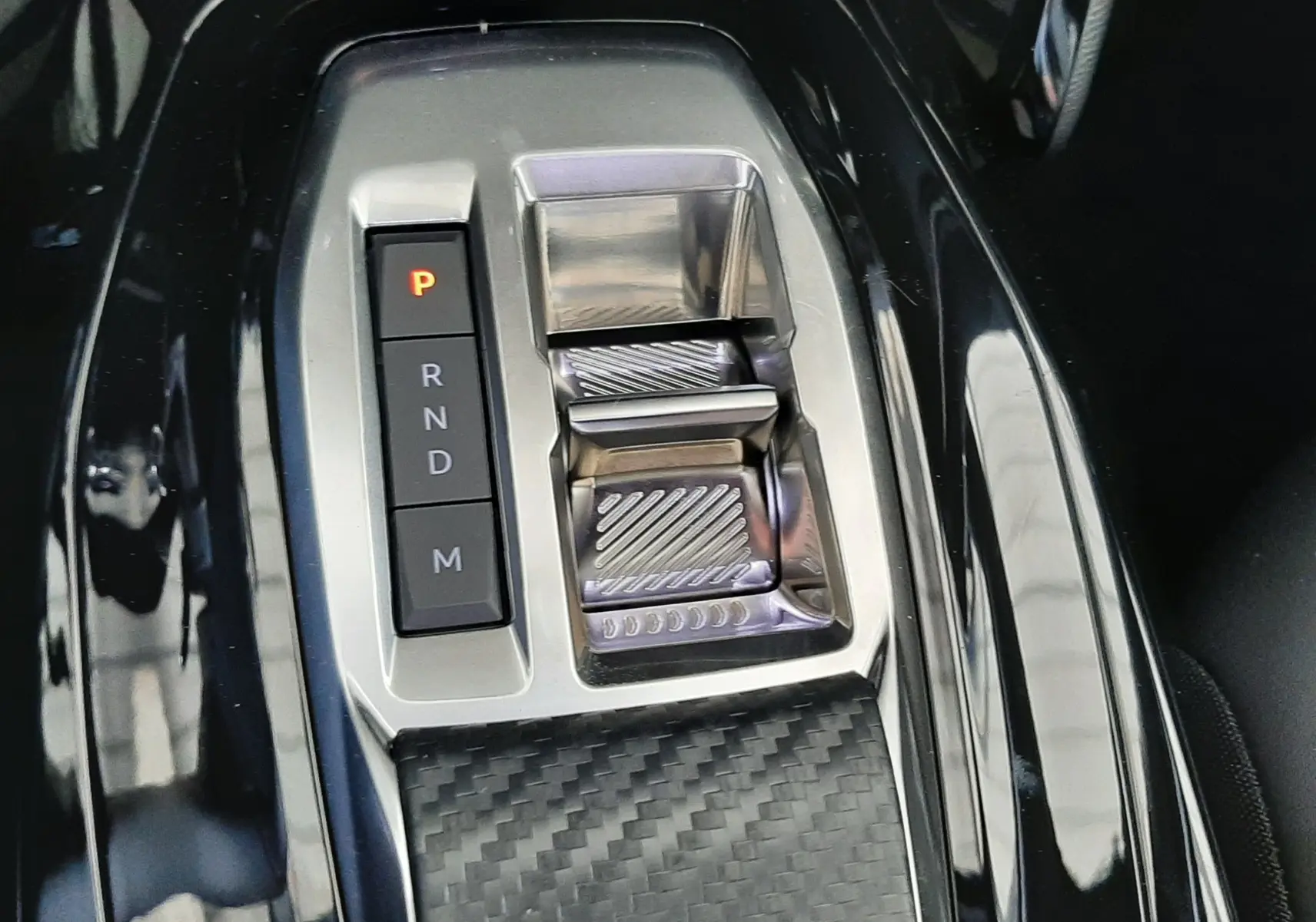 Gros plan sur la console centrale noire avec sélecteur de boîte automatique et finition carbone du Peugeot 2008 gris Artense.