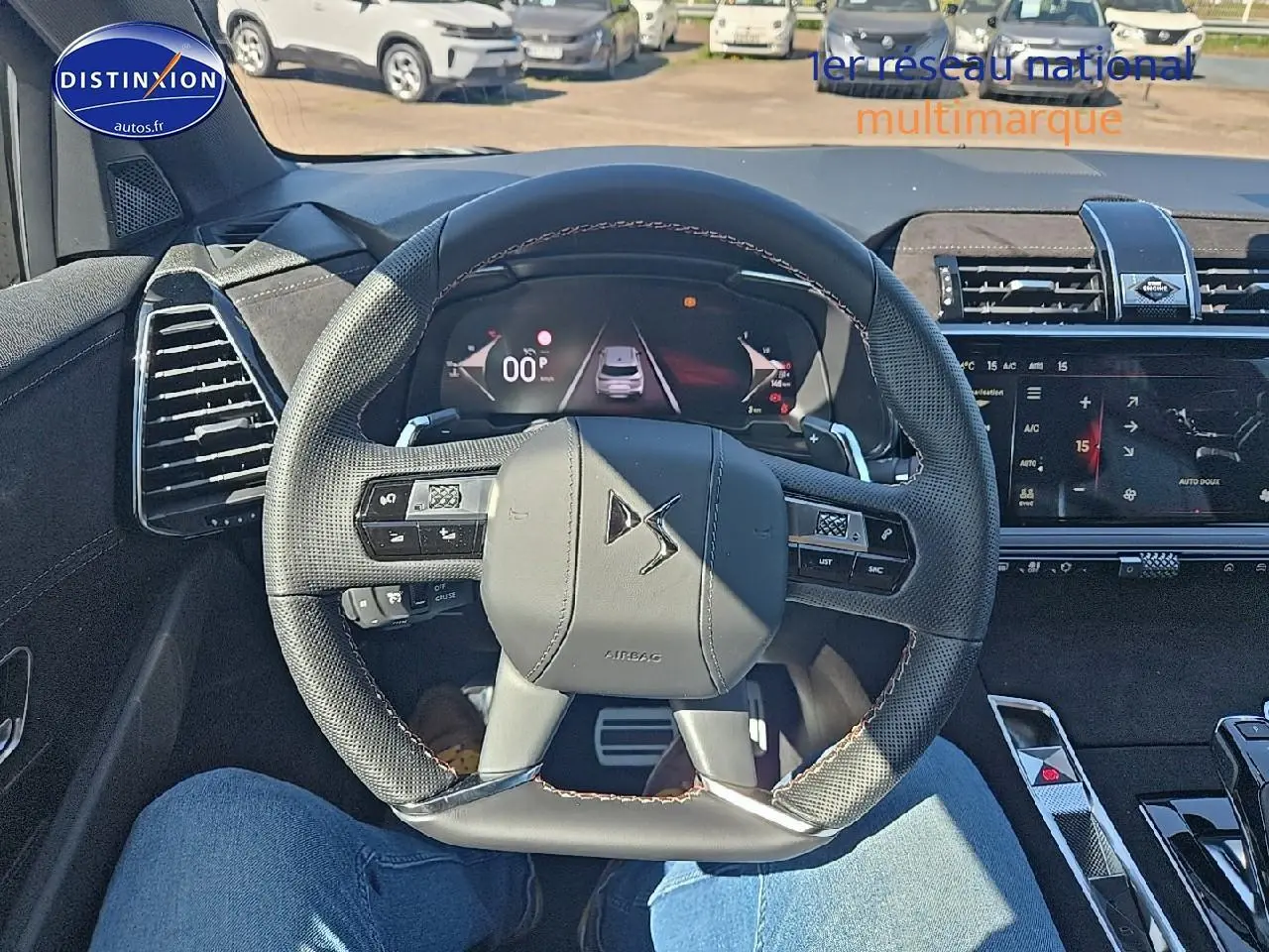 Vue intérieure centrée sur le volant cuir DS d'un DS7 2025 avec tableau de bord numérique et écran tactile.
