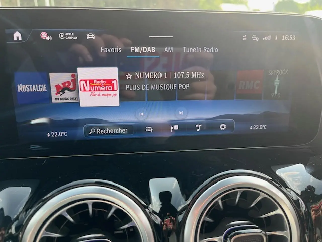 Écran tactile central du Mercedes GLA 250 e blanc 2024 affichant la radio FM/DAB et la température à 22°C