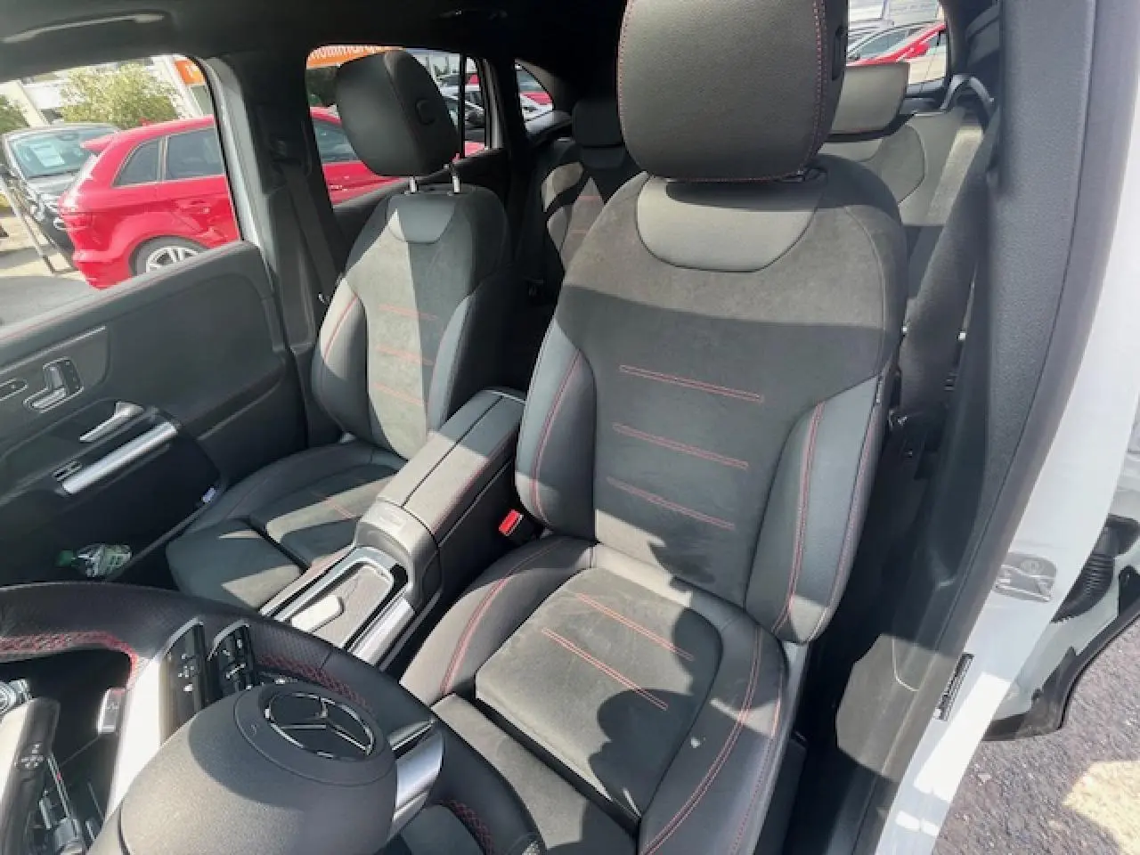 Vue intérieure côté conducteur du Mercedes GLA 250 e blanc, sièges sport en alcantara noir avec surpiqûres rouges.