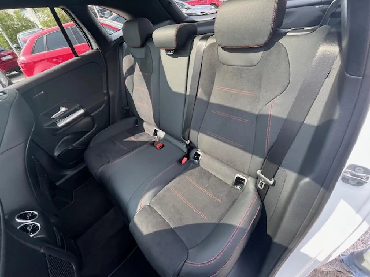 Vue côté droit des sièges arrière en alcantara noir avec surpiqûres rouges dans une Mercedes GLA 250 e hybride blanche 2024.