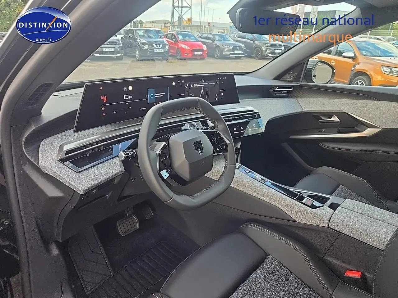 Intérieur du Peugeot 3008 2025 vu côté conducteur, volant cuir et tableau de bord numérique large avec finitions tissu gris.