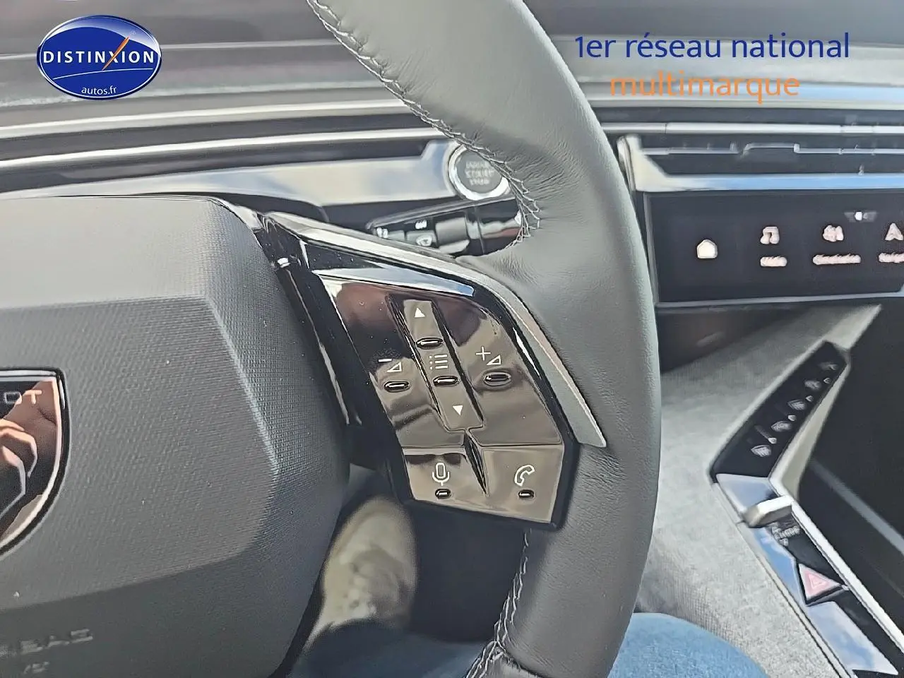 Gros plan sur les commandes au volant cuir noir du Peugeot 3008 2025 hybride, avec écran tactile en arrière-plan.