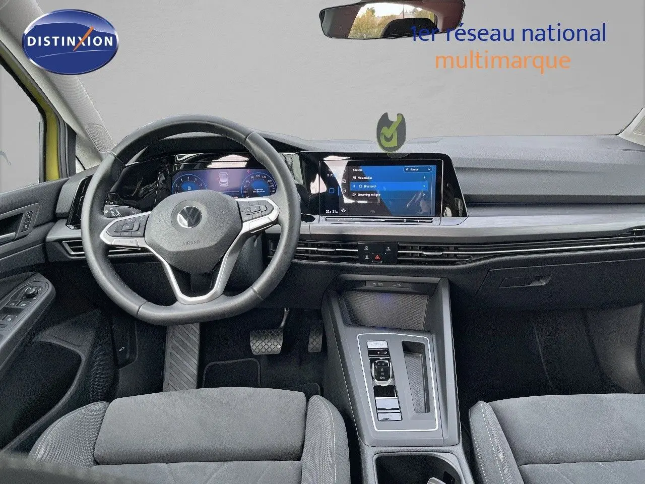 Vue intérieure avant de la Volkswagen Golf jaune 1.5 eTSI 150CH DSG7 STYLE, tableau de bord moderne avec écran tactile central.