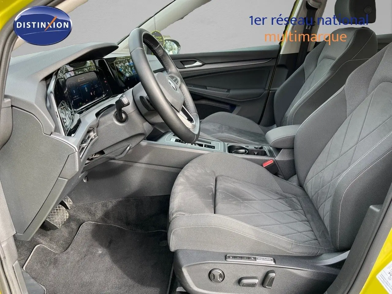 Vue intérieure côté conducteur de la Volkswagen Golf jaune 2020, sièges gris avec surpiqûres et tableau de bord digital.