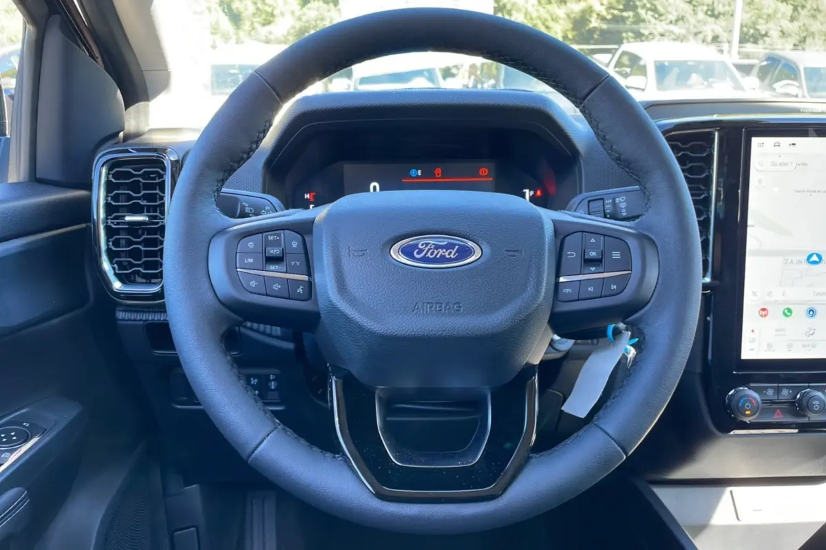 Vue rapprochée du volant noir du Ford Ranger 2025 TDCI 170 BVA XLT avec commandes intégrées et tableau de bord digital.